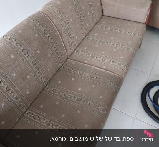 ספה חומה עם דוגמה, צינור ניקוי על הרצפה